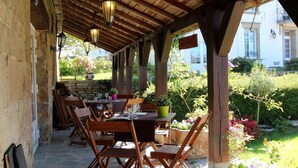 An outdoor patio with wooden tables and chairs, stone walls, and hanging lanterns. - Logis Auberge de Kerveoc'h (Douarnenez)