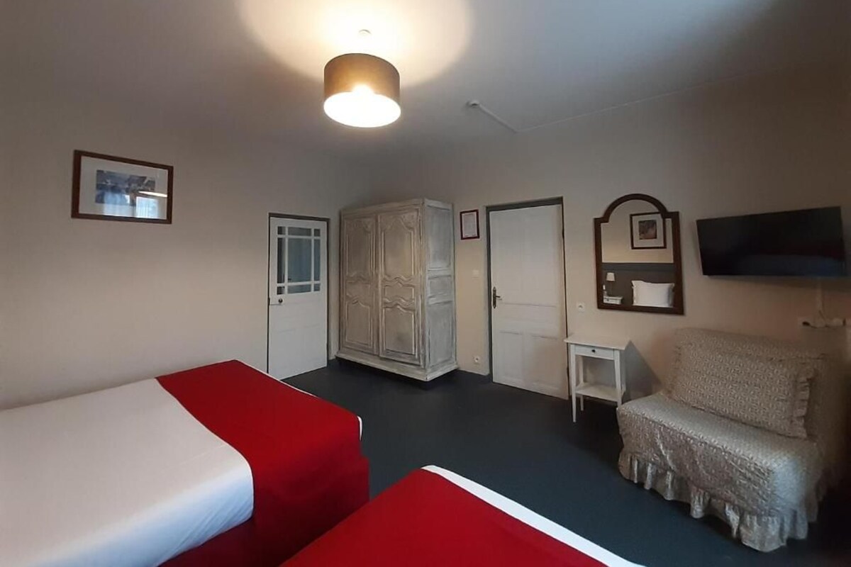 Una habitación de hotel con dos camas, un armario, un televisor y una mesita.