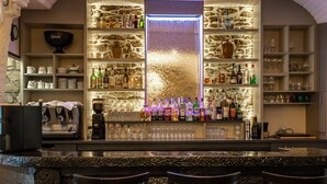 A bar area with a stone wall, shelves with bottles and glasses, and a central waterfall feature. - Logis Auberge de Kerveoc'h (Douarnenez)