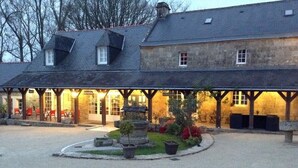 A building with a covered outdoor seating area, stone planters, and a central fountain. - Logis Auberge de Kerveoc'h (Douarnenez)
