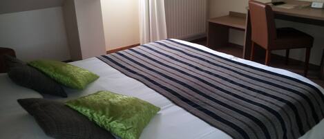 Un dormitorio con cama, escritorio y silla.