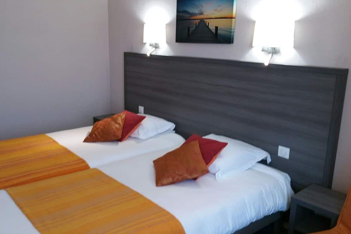 A double bed with a striped bedspread and two pillows, a nightstand, and a wall-mounted light fixture.