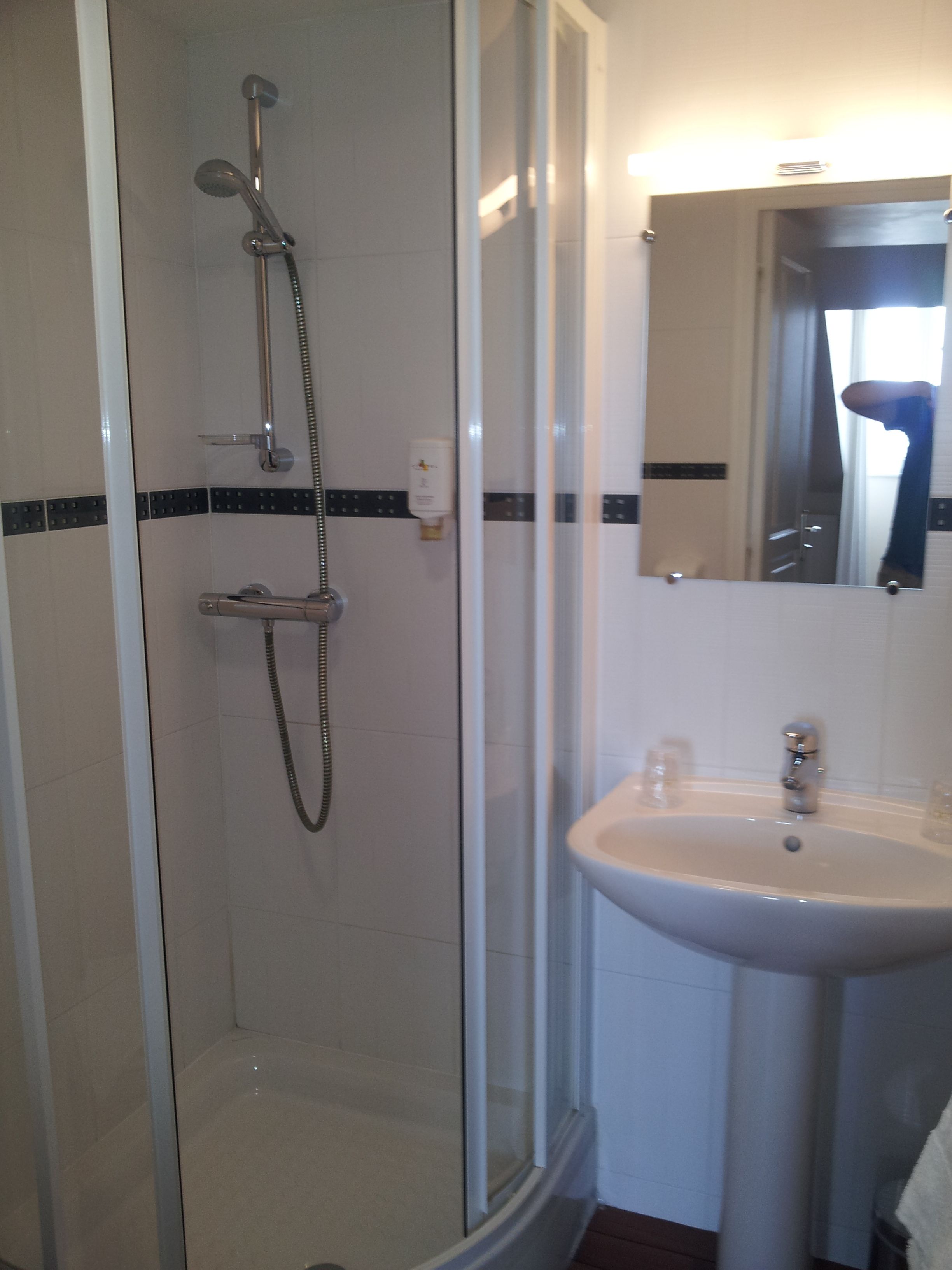 A bathroom with a glass-enclosed shower, a sink, and a mirror.