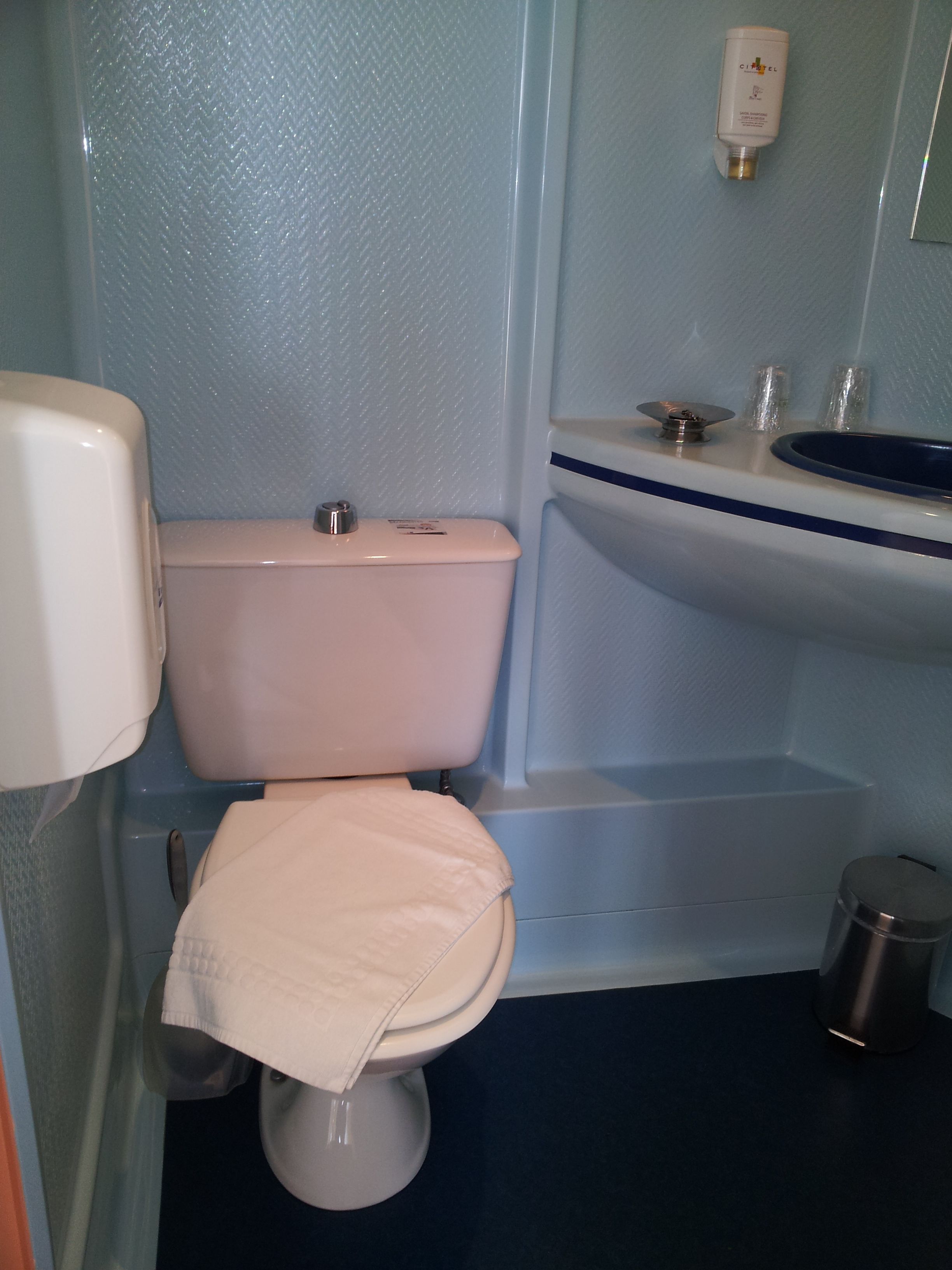 A bathroom with a toilet, sink, and hand dryer.