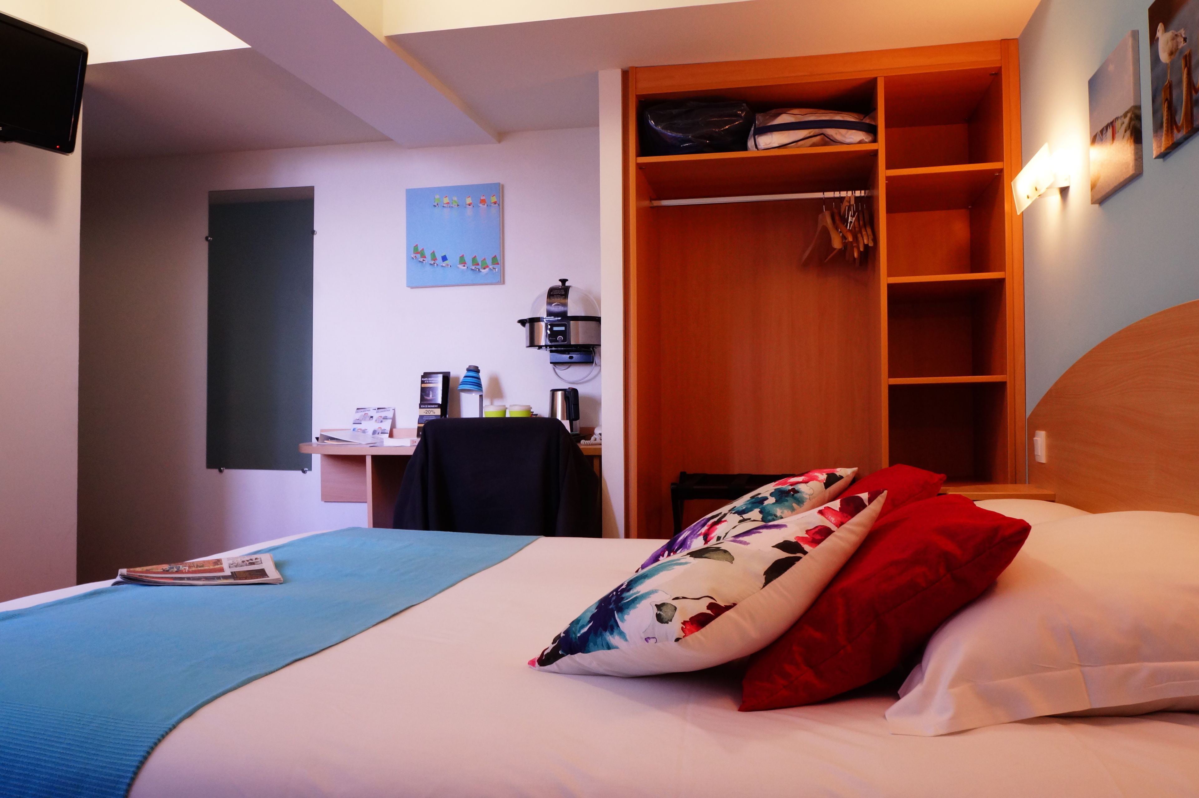 A bedroom with a bed, a desk, and a wardrobe.