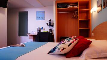 A bedroom with a bed, a desk, and a wardrobe.