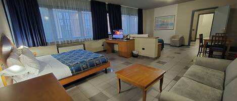 A hotel room with a bed, a desk, a sofa, and a small table.
