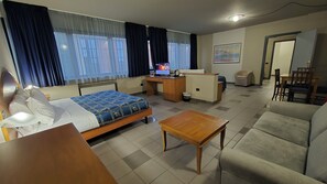 Et hotelværelse med seng, skrivebord, sofa og et lille bord.