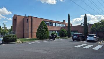 Un parking avec un bâtiment en briques, une moto et des voitures.