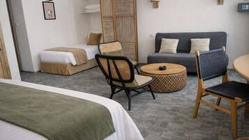 Ein Hotelzimmer mit einem Bett, einem Sofa, einem Esstisch und einem Stuhl. An der Wand befinden sich Wandlampen und ein Bilderrahmen.