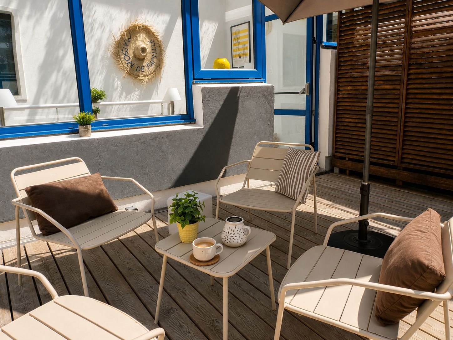 An outdoor seating area with metal chairs and tables, a potted plant, and a coffee cup.
