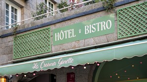 A hotel bistro with outdoor seating, a green awning, and a sign reading "Hôtel Bistro."
