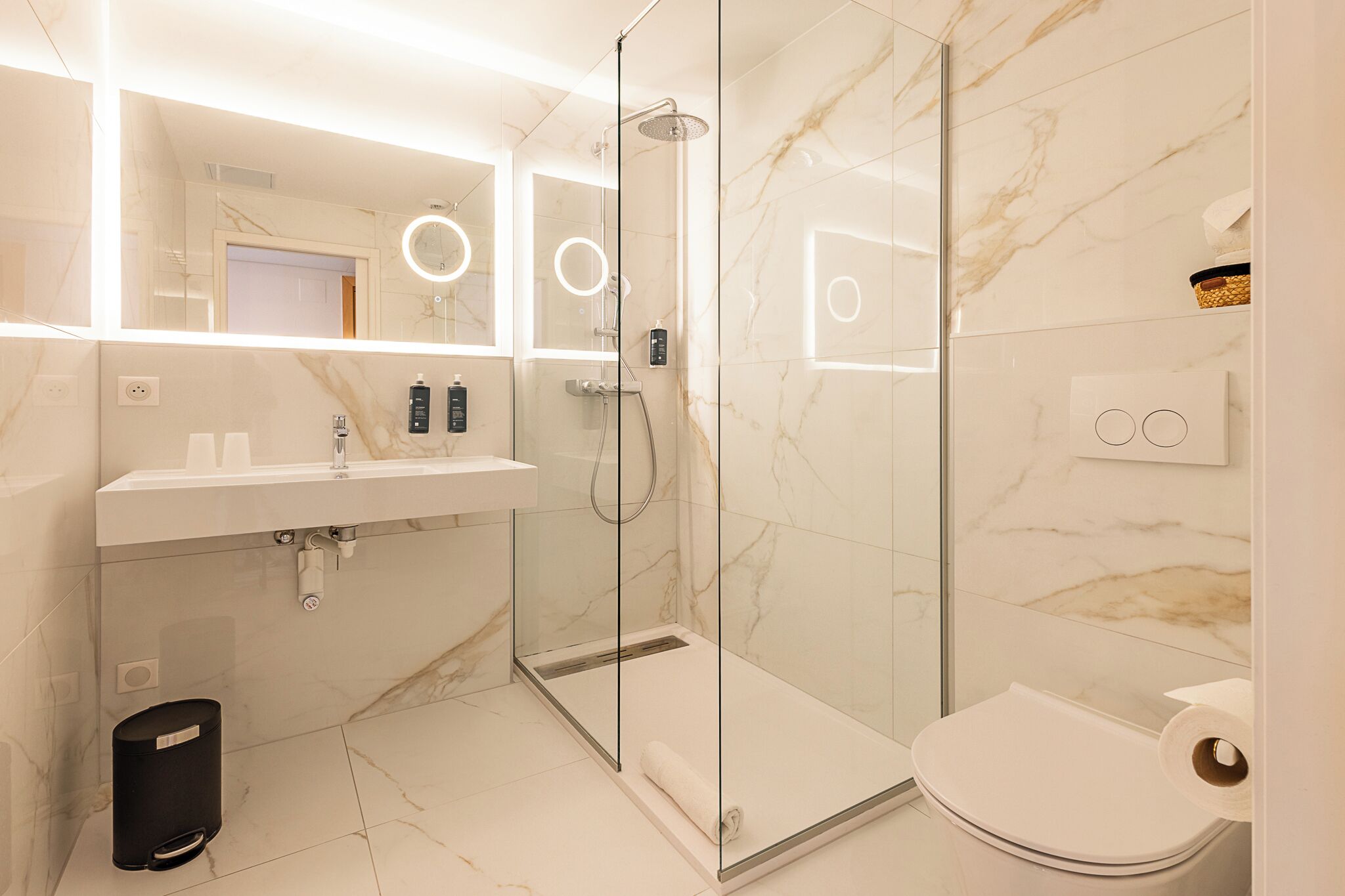 A modern bathroom with a glass-enclosed shower, a white sink, and a toilet.