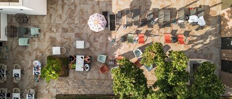 An aerial view of a hotel with a swimming pool, outdoor seating, and greenery.