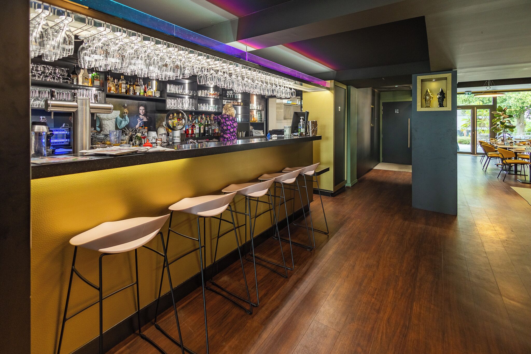 A bar area with stools, a counter with bottles, and a mural.
