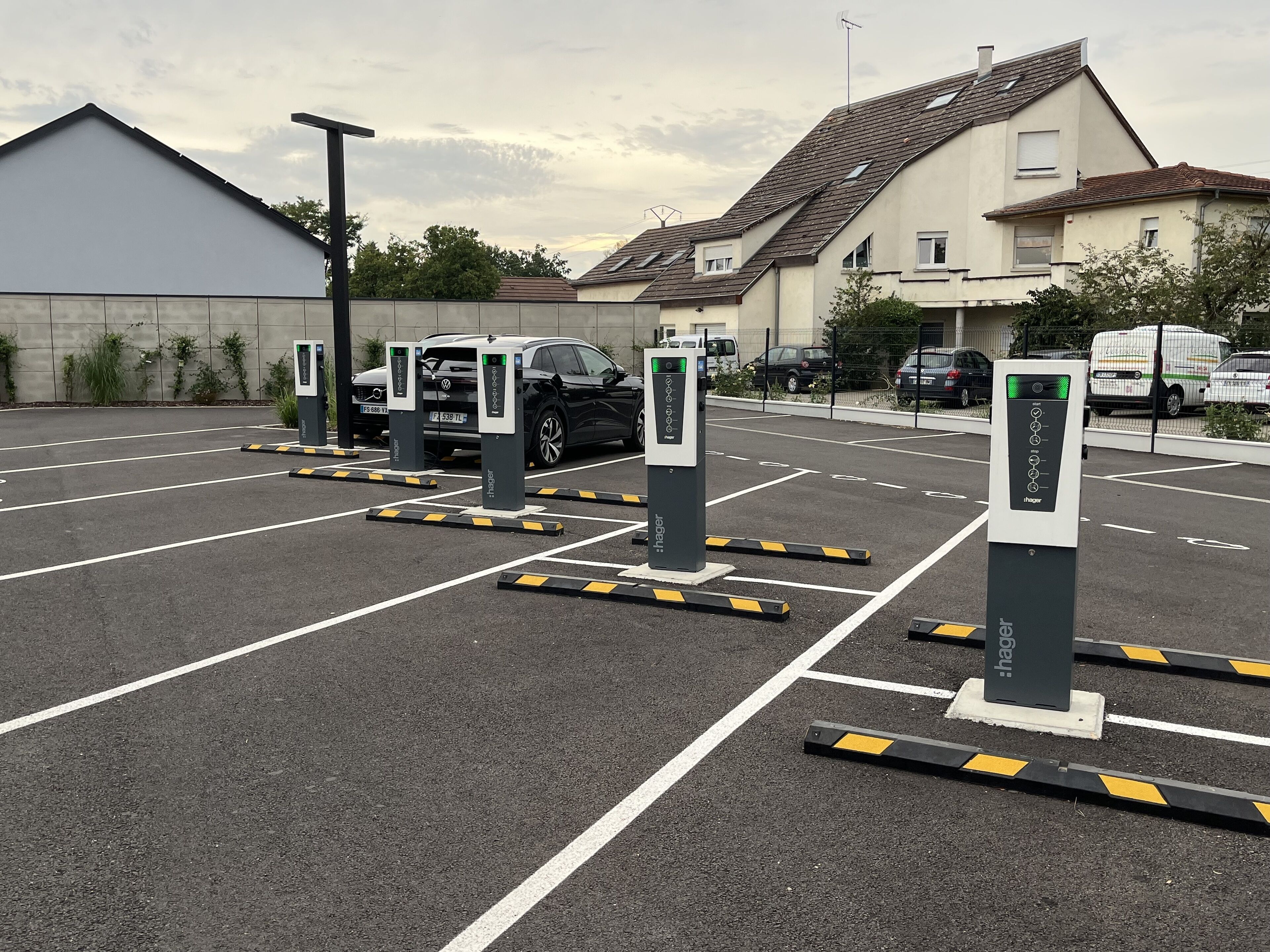 A parking lot with electric vehicle charging stations, marked parking spaces, and a building in the background.