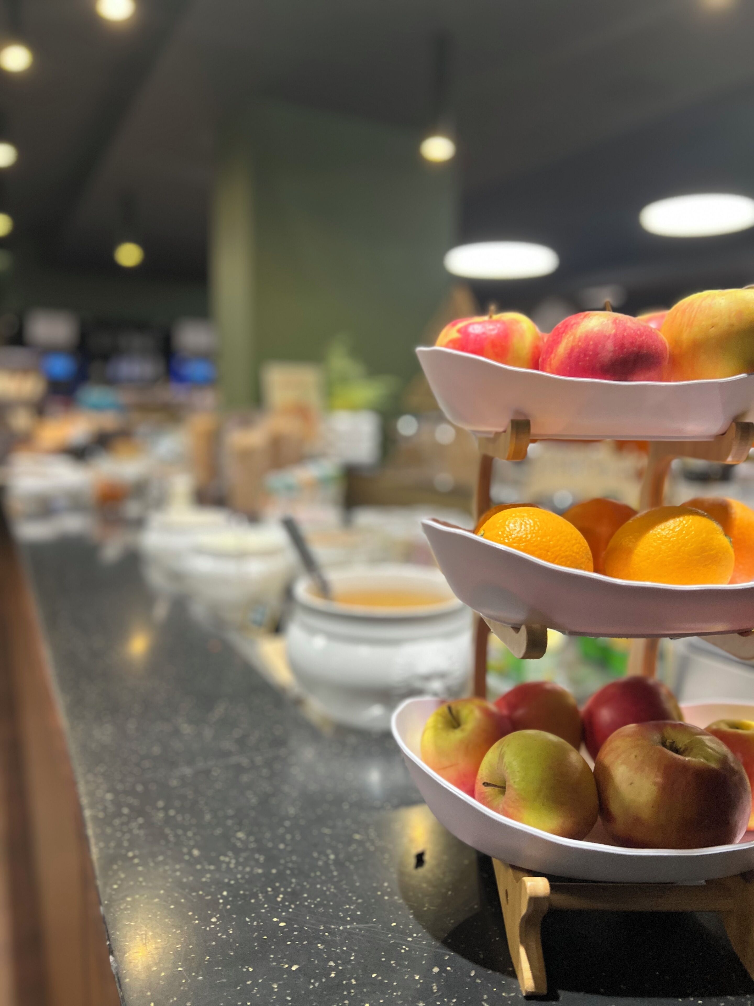 Ein reichhaltiges Buffet mit verschiedenen Servierbehältern, darunter Obst und eine Suppenschüssel.