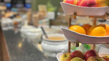 Ein reichhaltiges Buffet mit verschiedenen Servierbehältern, darunter Obst und eine Suppenschüssel.