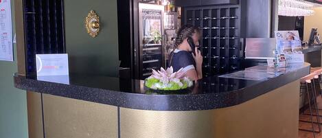 A reception area with a counter, a decorative plant, and a visible door leading to another room.