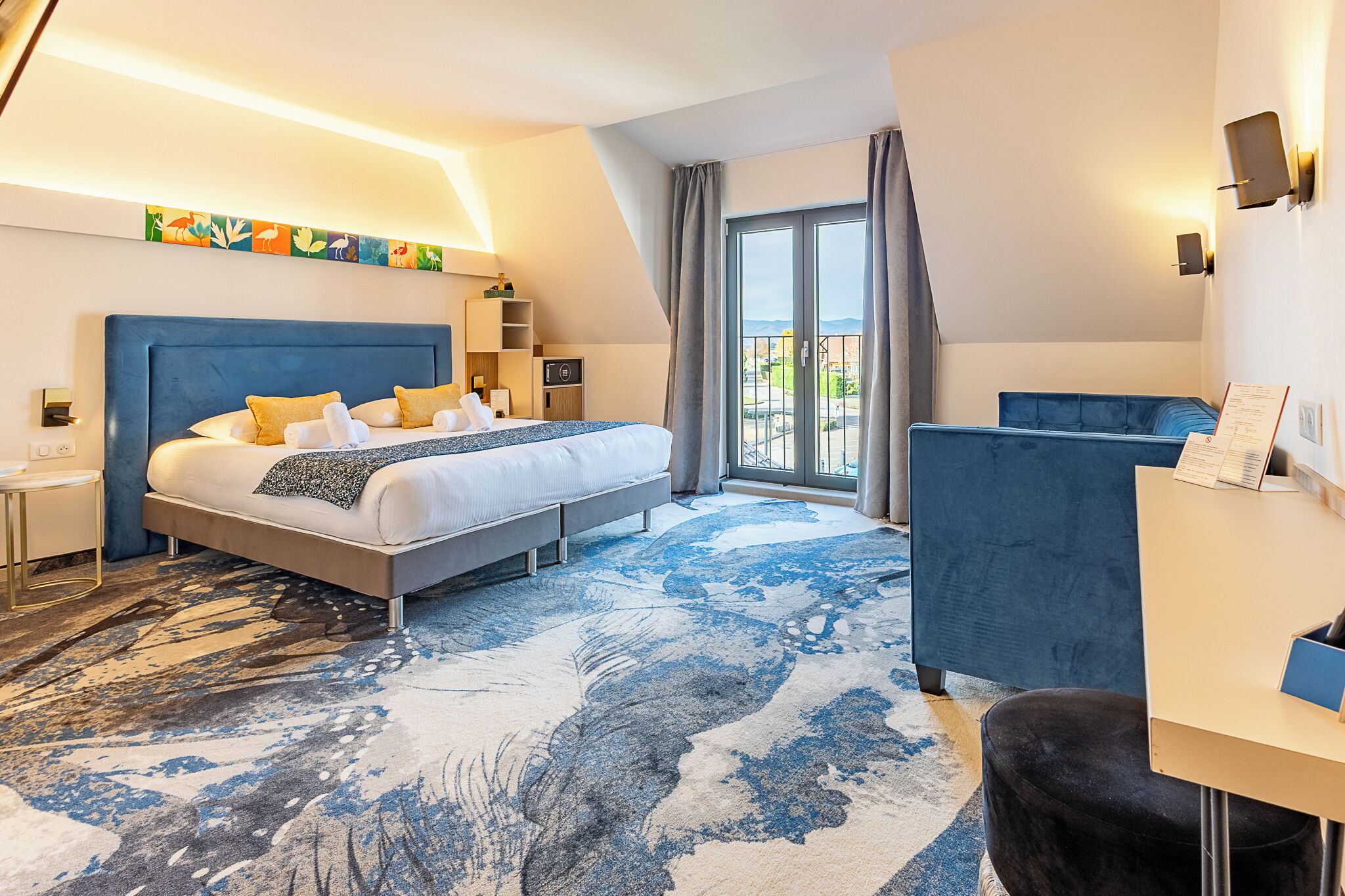 Une chambre d’hôtel moderne, dotée d’un grand lit, d’un bureau et offrant une vue sur l’extérieur.
