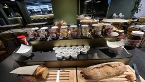 A buffet setup with various food items and condiments, including jars of spreads and bread on wooden boards. - Brit Hotel et Spa COLMAR EAST (Bischwihr)