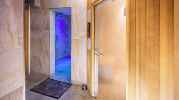 A hallway leading to a spa room with a wooden door and a tiled floor.