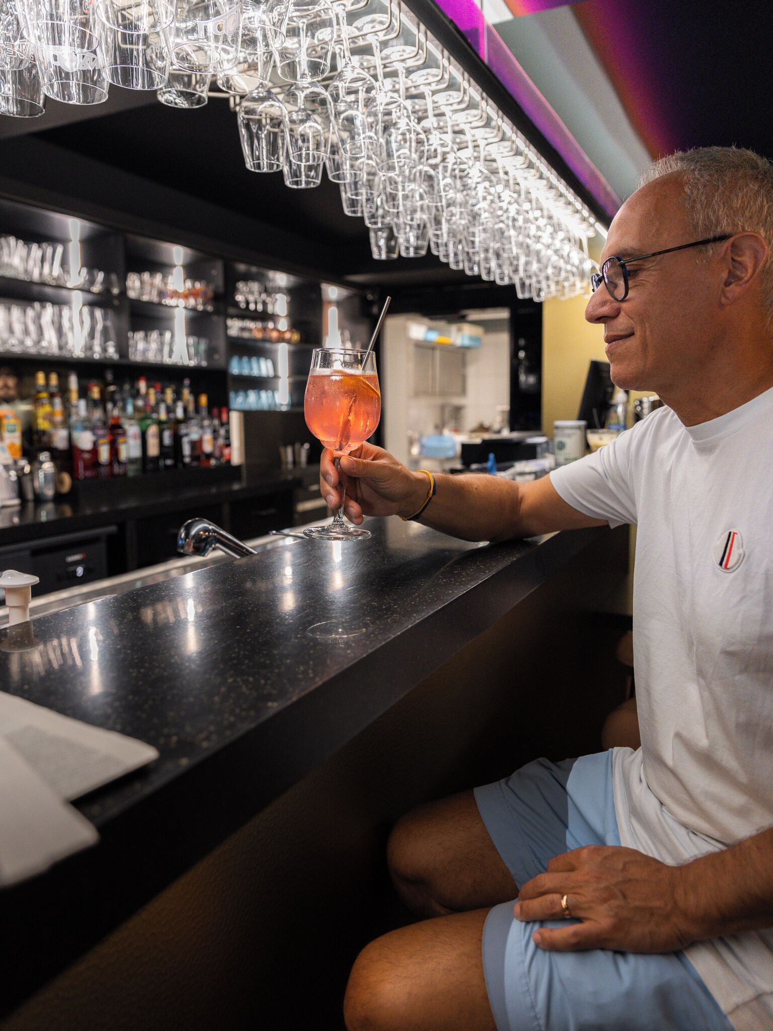 Zona de bar con una persona sosteniendo una copa de cóctel.