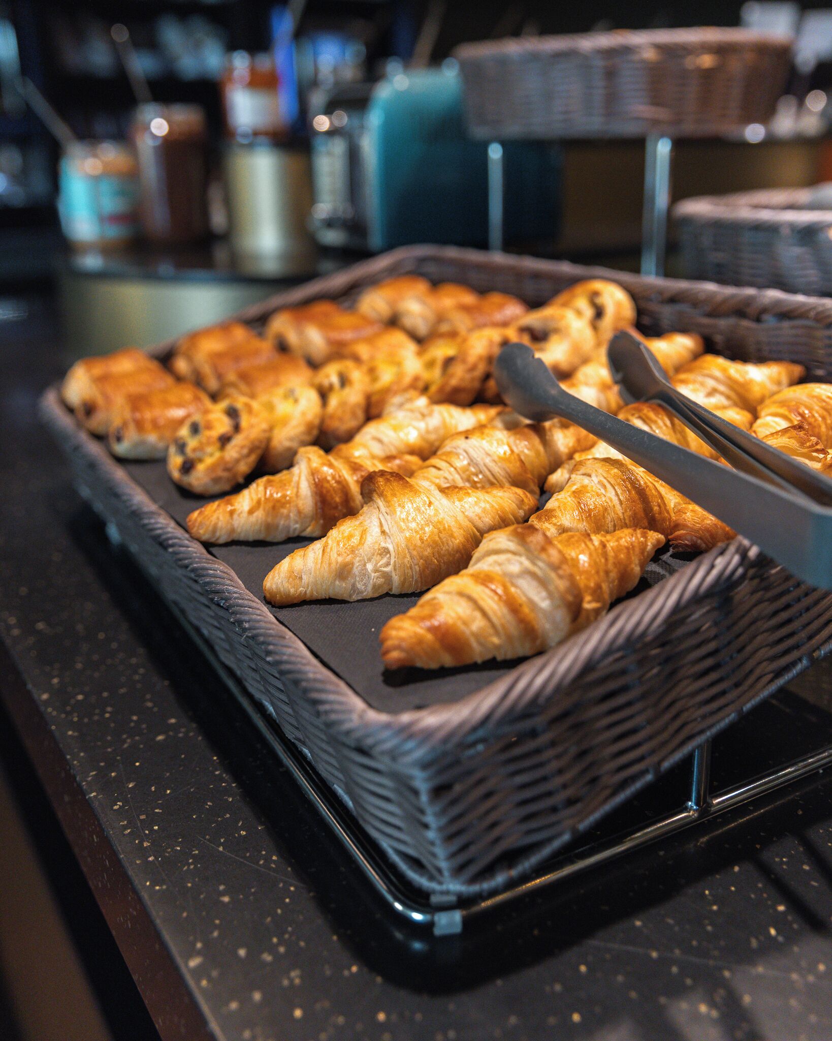 Una bandeja con diversos pasteles, incluyendo croissants, sobre una encimera negra.