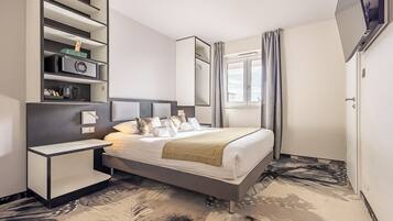 A modern hotel room with a bed, bedside tables, a built-in TV, a wardrobe, and a window with curtains.