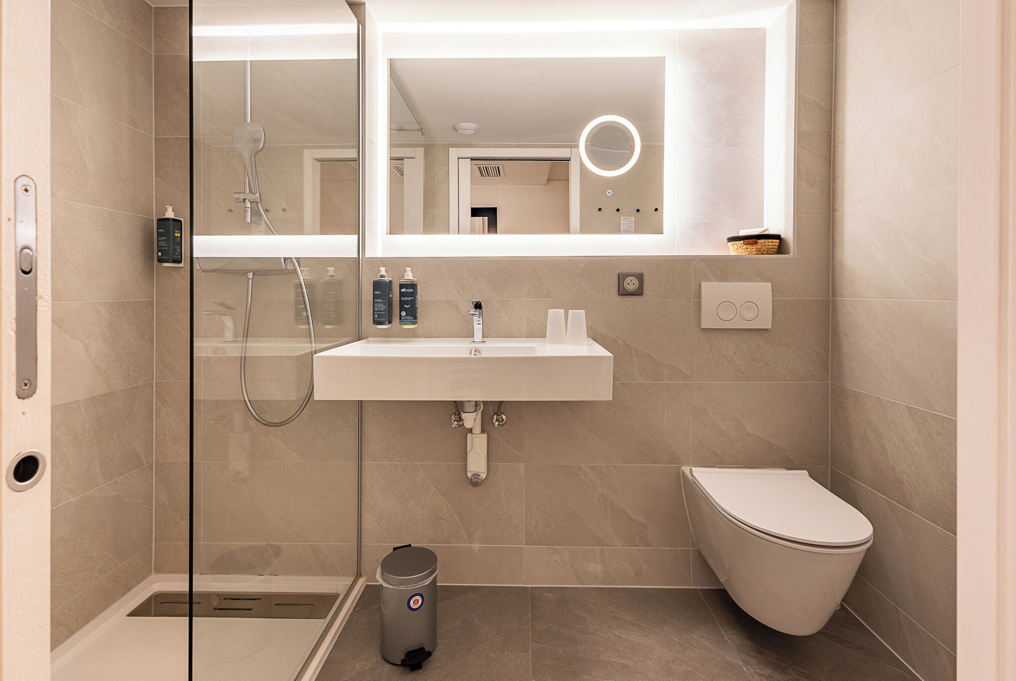A modern bathroom with a glass-enclosed shower, a white sink, and a toilet.