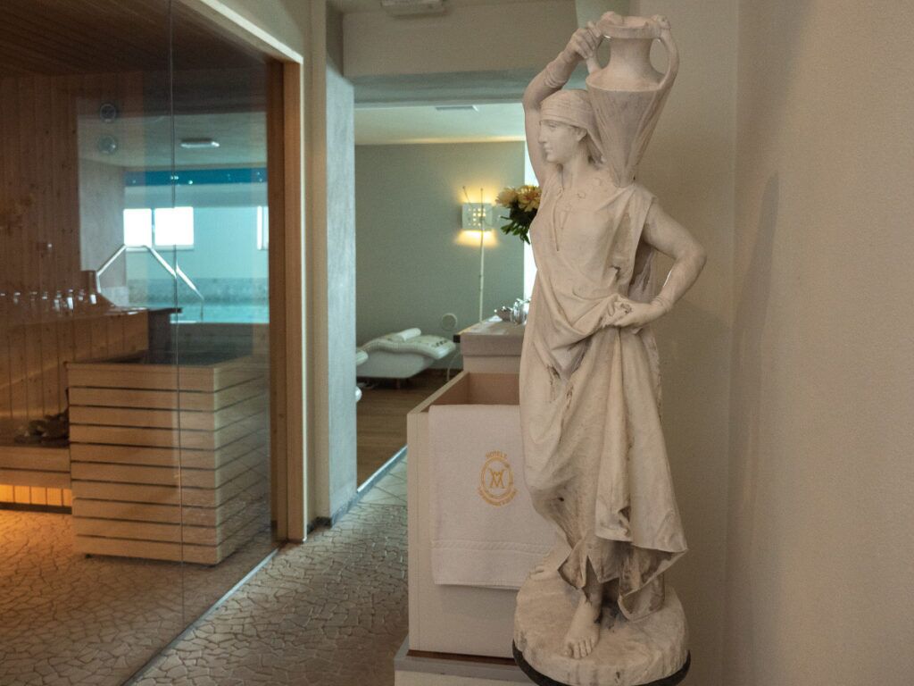 A marble statue in a lobby with a reception desk and a glass partition.