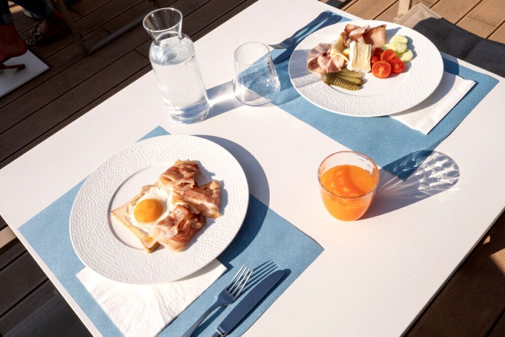 Ein Tisch mit Frühstücksteller, einem Glas Orangensaft und einer Wasserflasche.
