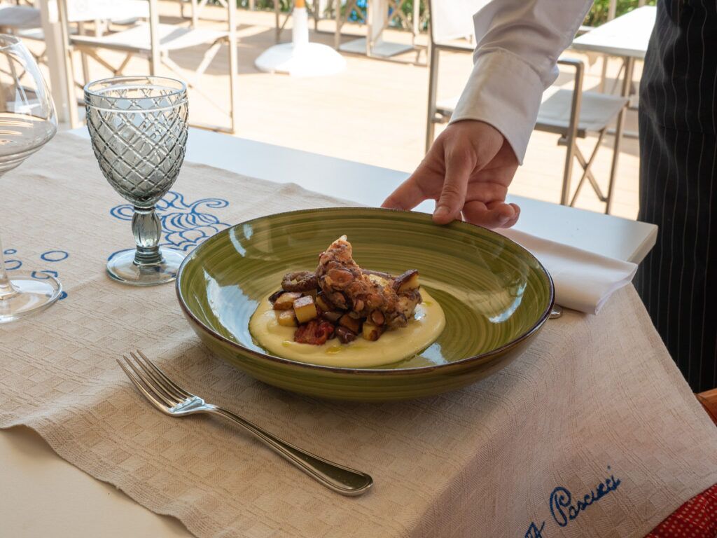 A dining table with a green plate of food, a fork, and a glass.