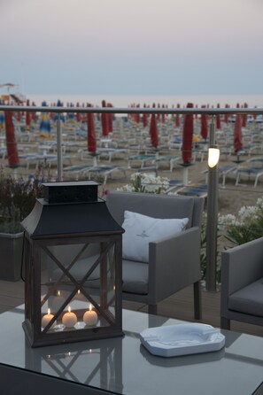 A glass table with a white ashtray and a lit lantern with candles. - Vidi Miramare & Delfino (Jesolo)