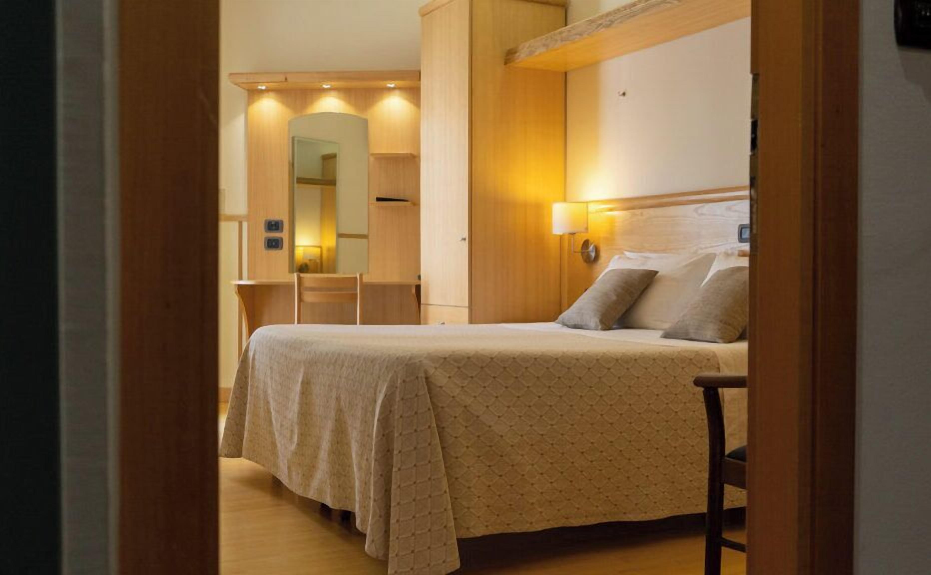 Ein Hotelzimmer mit Bett, Stuhl, Schreibtisch und Spiegel.