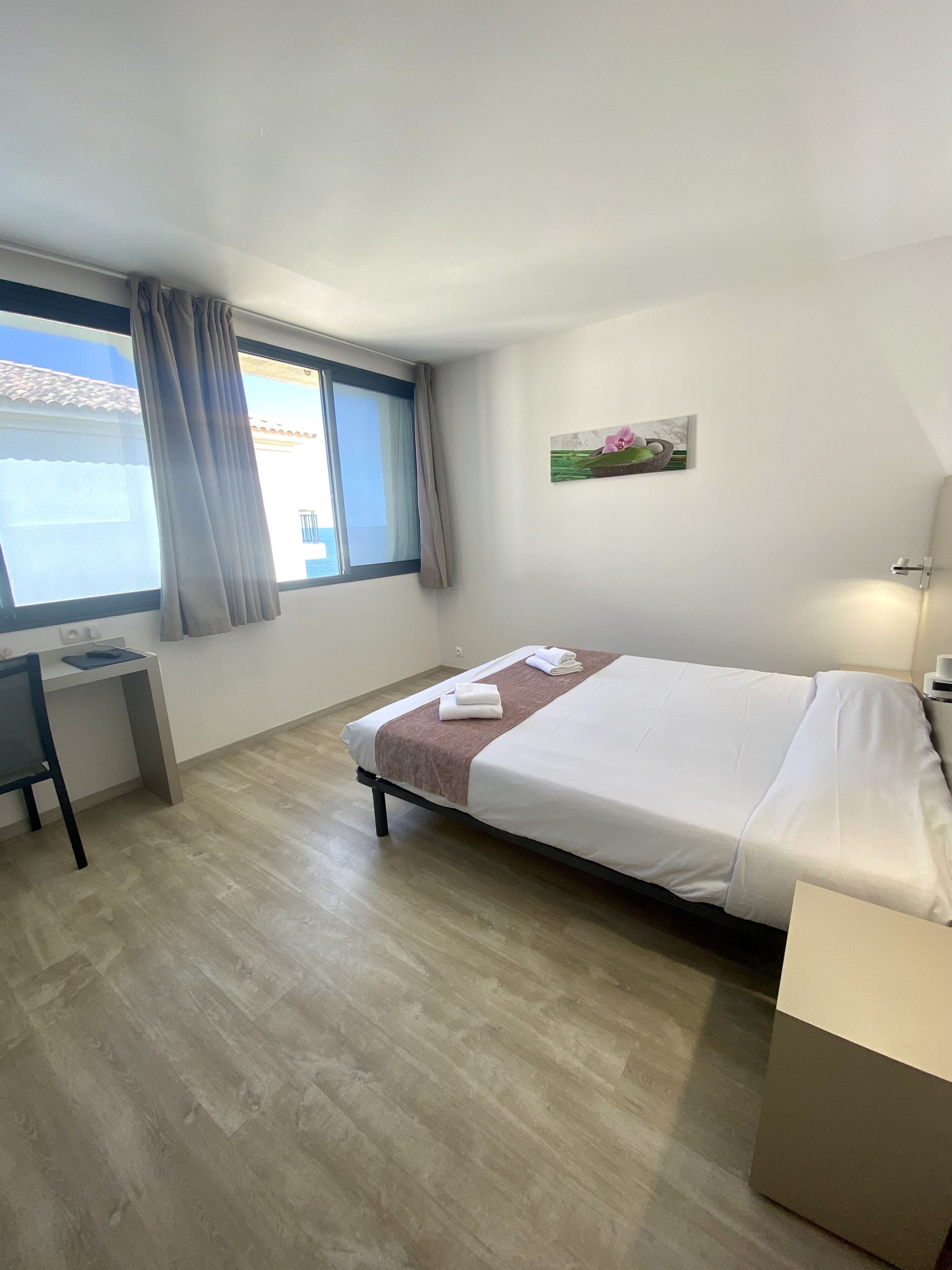 Una habitación de hotel con cama, escritorio y ventana con cortinas.