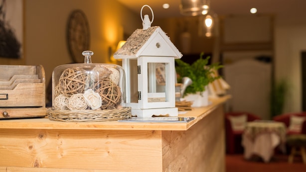 A wooden reception desk with a white lantern and a glass jar with decorative items. - The Originals Boutique, Hotel Le Kastelberg (Andlau)