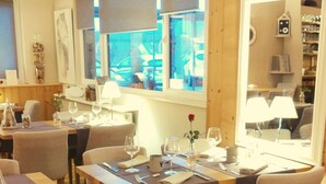 A dining area with tables set for two, equipped with cutlery, glasses, and a vase with a flower. - The Originals Boutique, Hotel Le Kastelberg (Andlau)