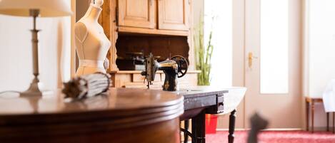 A vintage sewing machine on a wooden table, a mannequin, and a lamp in a room with wooden cabinets and a red carpet.