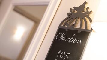 Une plaque noire avec une inscription blanche indiquant « Chambres 105 106 » est fixée à un mur.