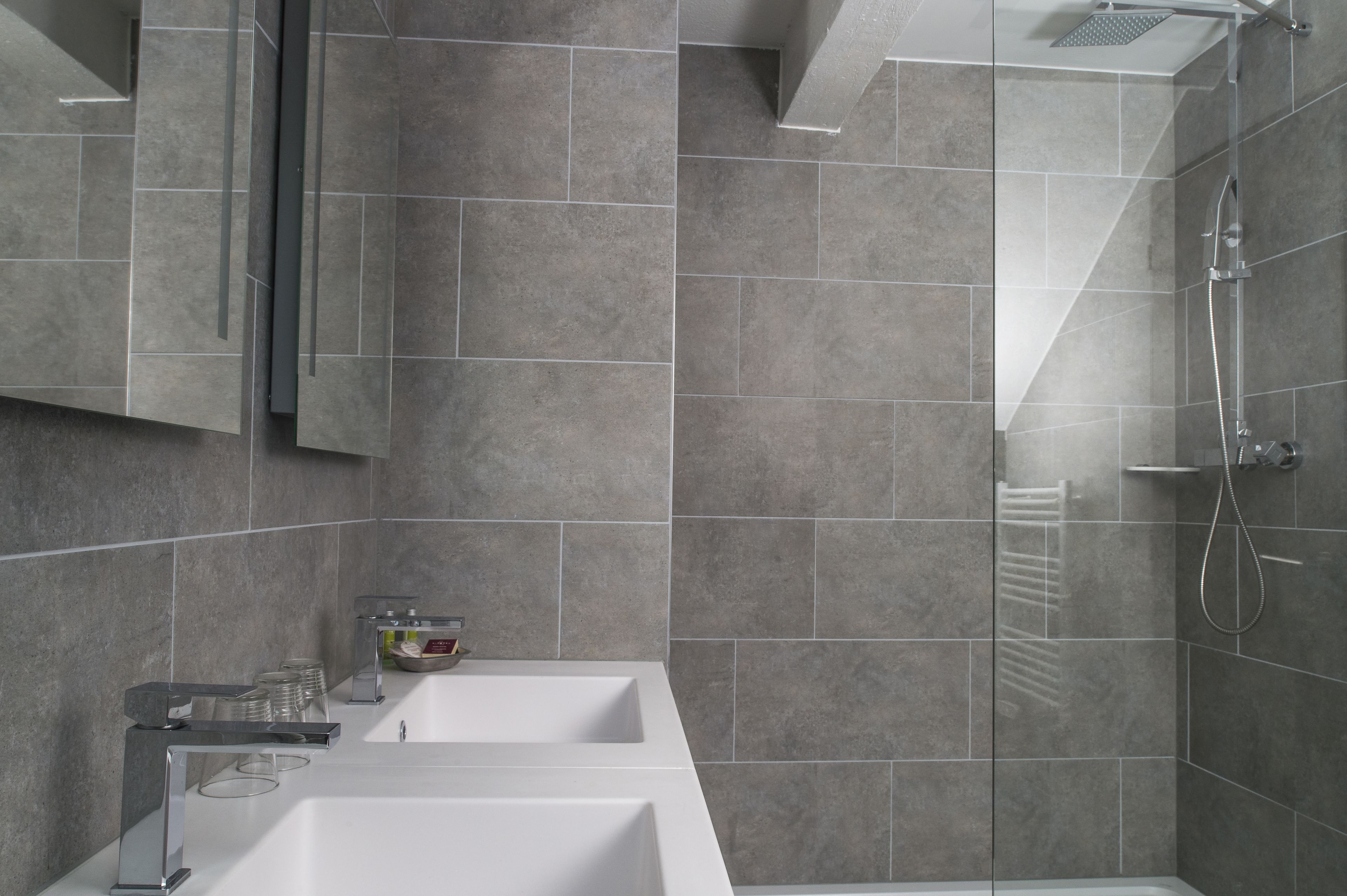 A modern bathroom with a large sink, mirror, and shower.