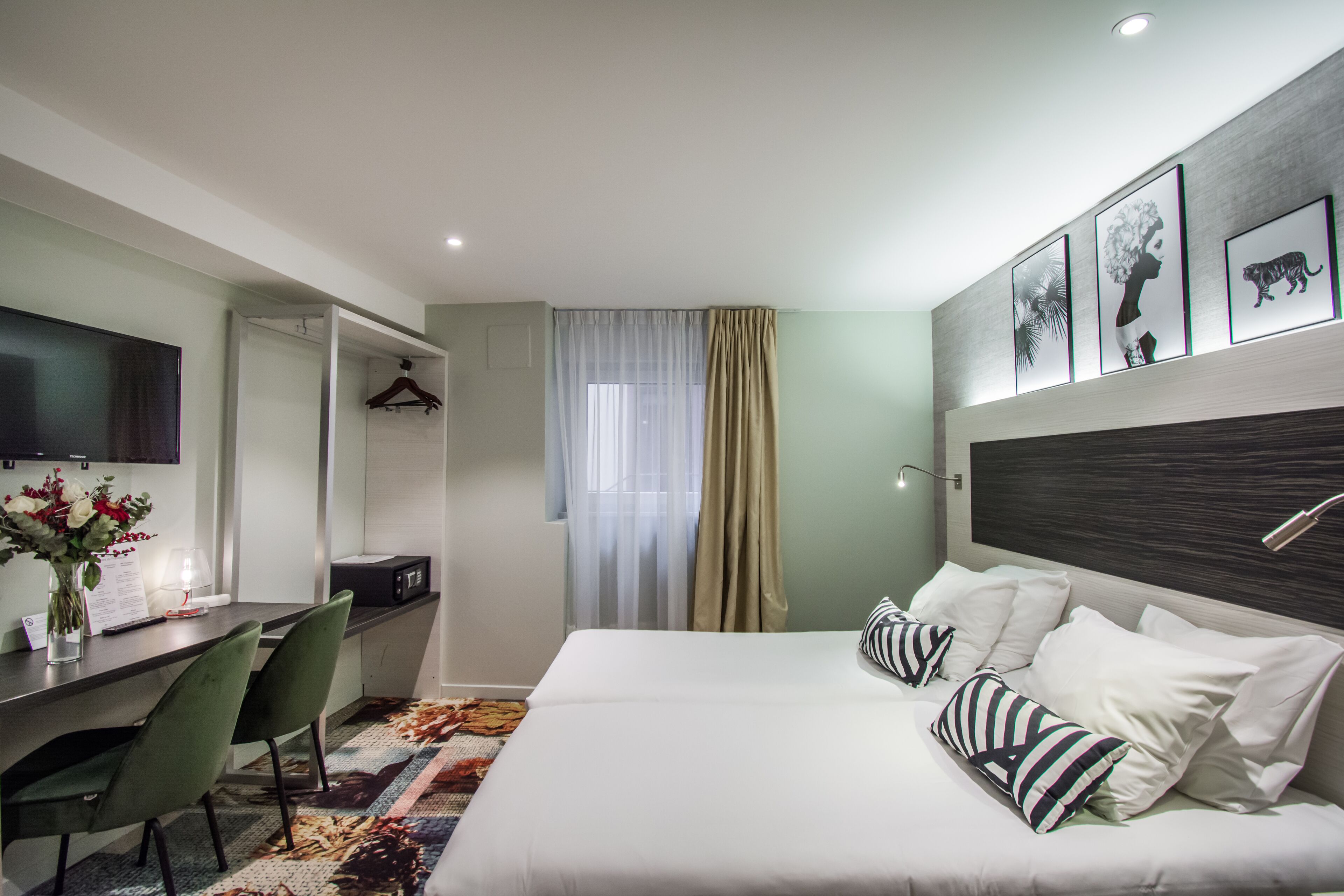 A hotel room with a bed, a desk, a chair, a TV, and a shower.