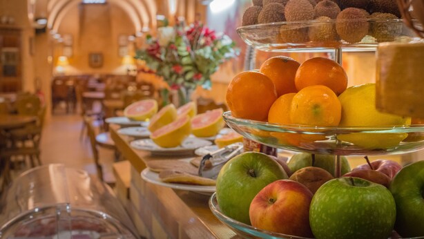 A buffet with a variety of fruits and desserts, including apples, oranges, and lychees. - Couvent du Franciscain (Strasbourg)