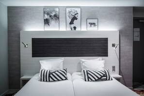 Ett modernt hotellrum med en stor säng, två sängbord och tre inramade konstverk på väggen.