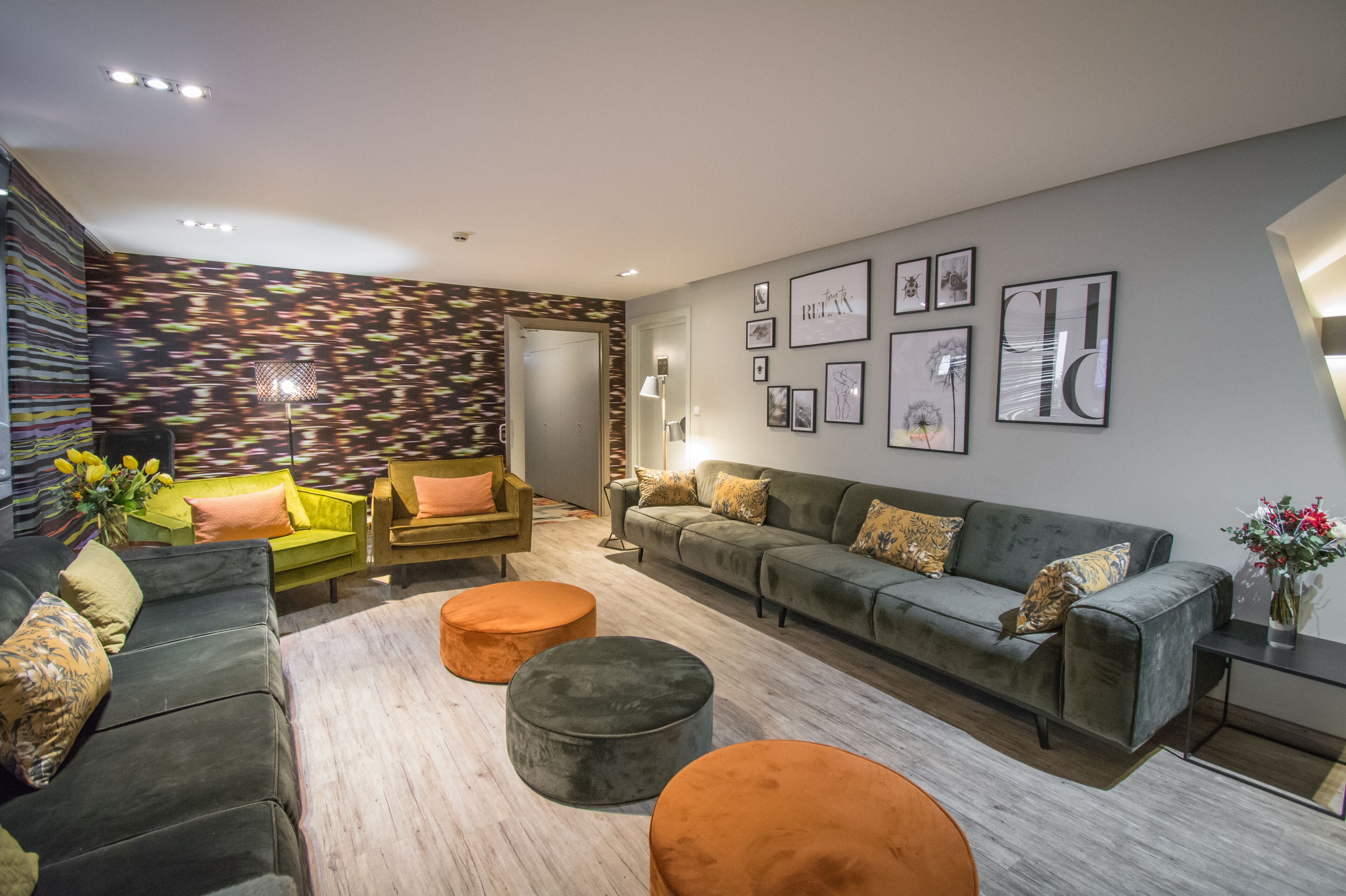 A modern living room with a sofa, ottomans, and a patterned wall.