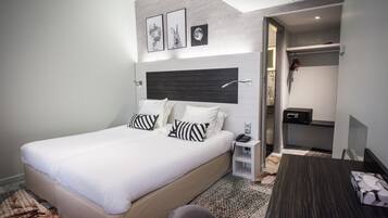 Quarto de hotel moderno com uma cama grande, mesas de cabeceira, uma escrivaninha e um closet espaçoso.