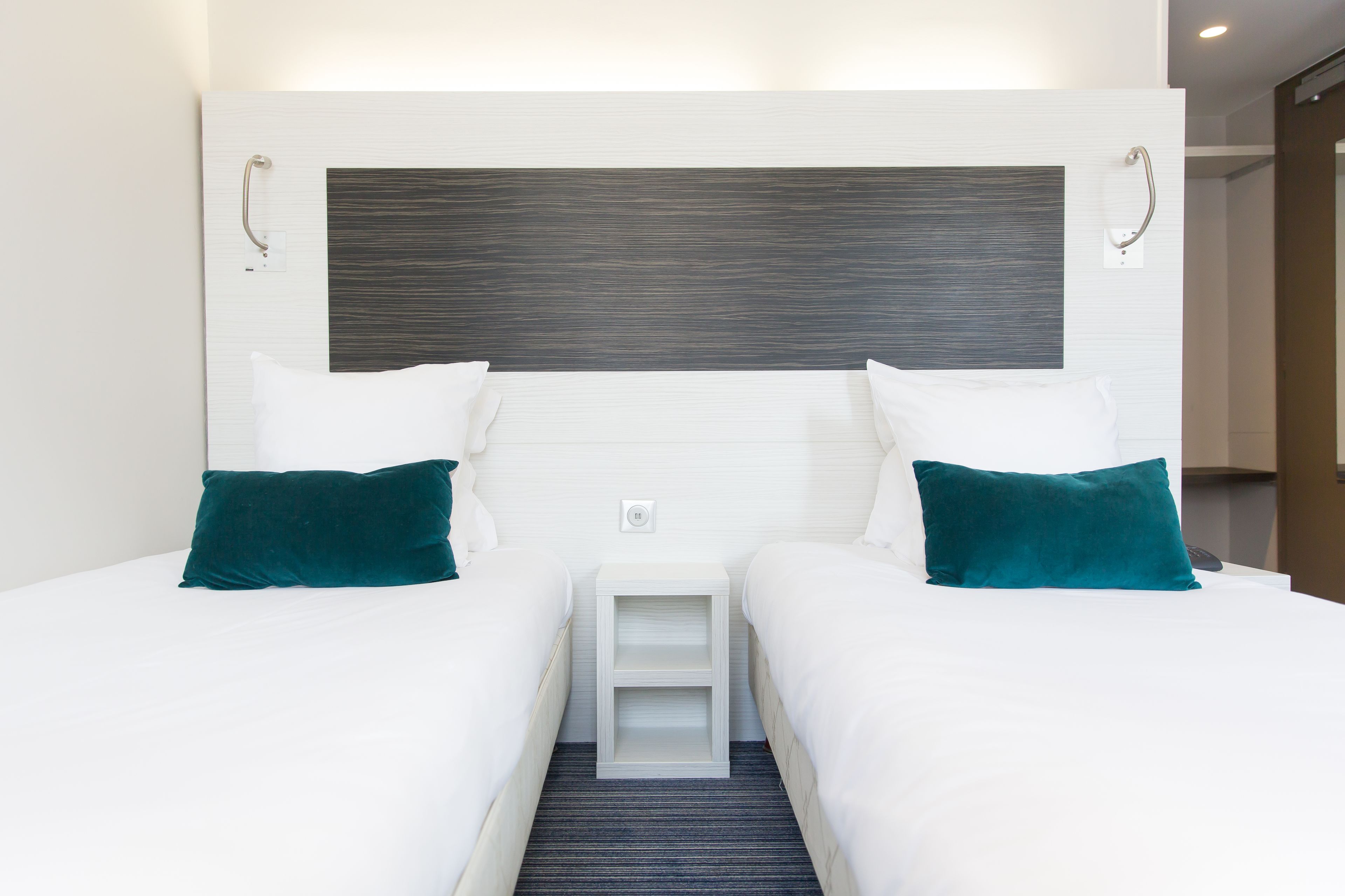 A double room with two beds, a bedside table, and a headboard.