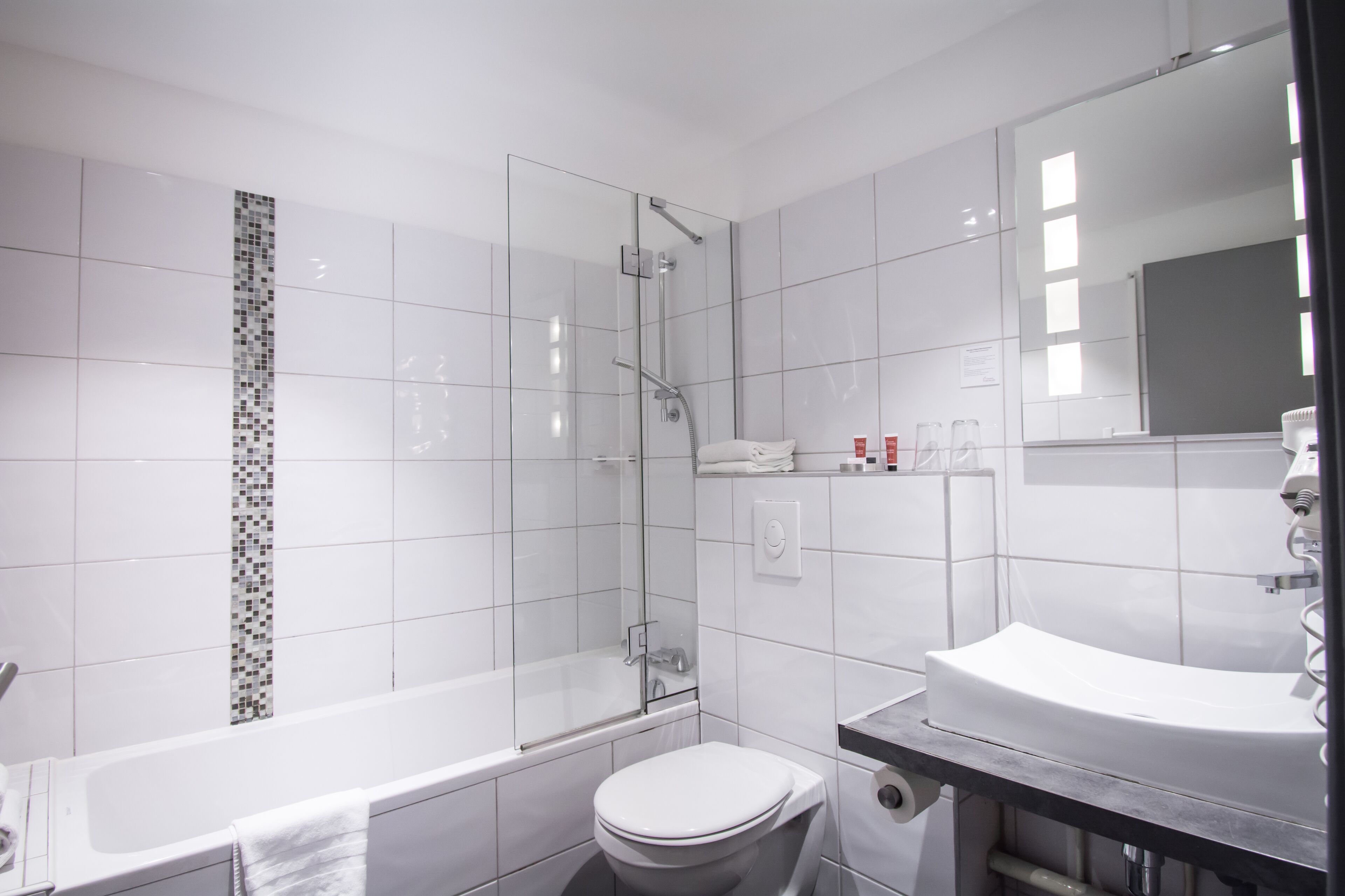 A modern bathroom with a glass-enclosed shower, a white toilet, and a sink with a mirror.