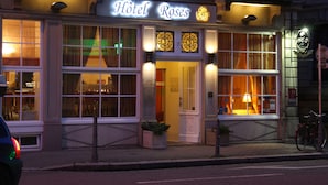 Hotel Roses, con una fachada clásica, amplias ventanas y una bicicleta estacionada afuera.