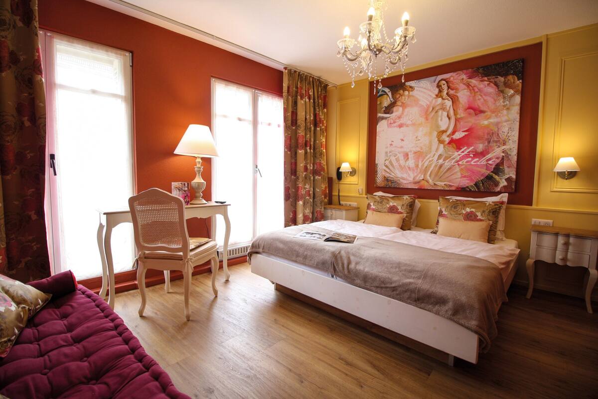 A spacious bedroom with a large bed, a desk, and a chair.